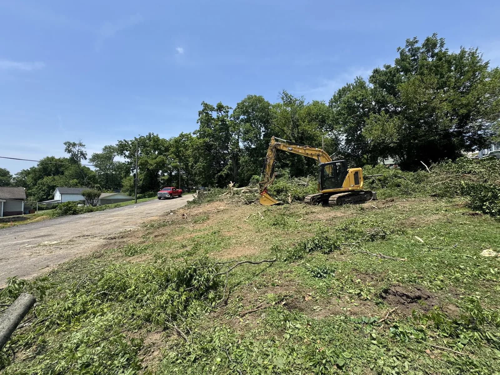Superior Land Management Cat excavator clearing trees and brush from a roadside residential lot for lot clearing