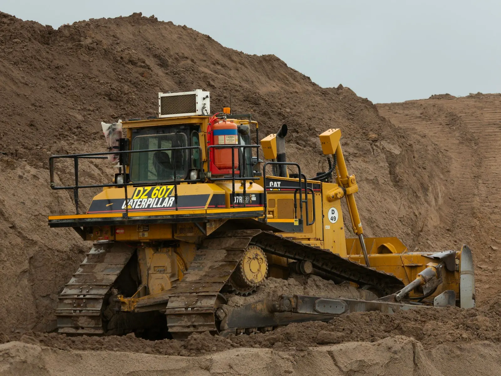 Caterpillar bulldozer pushing into a large pile of brown earth